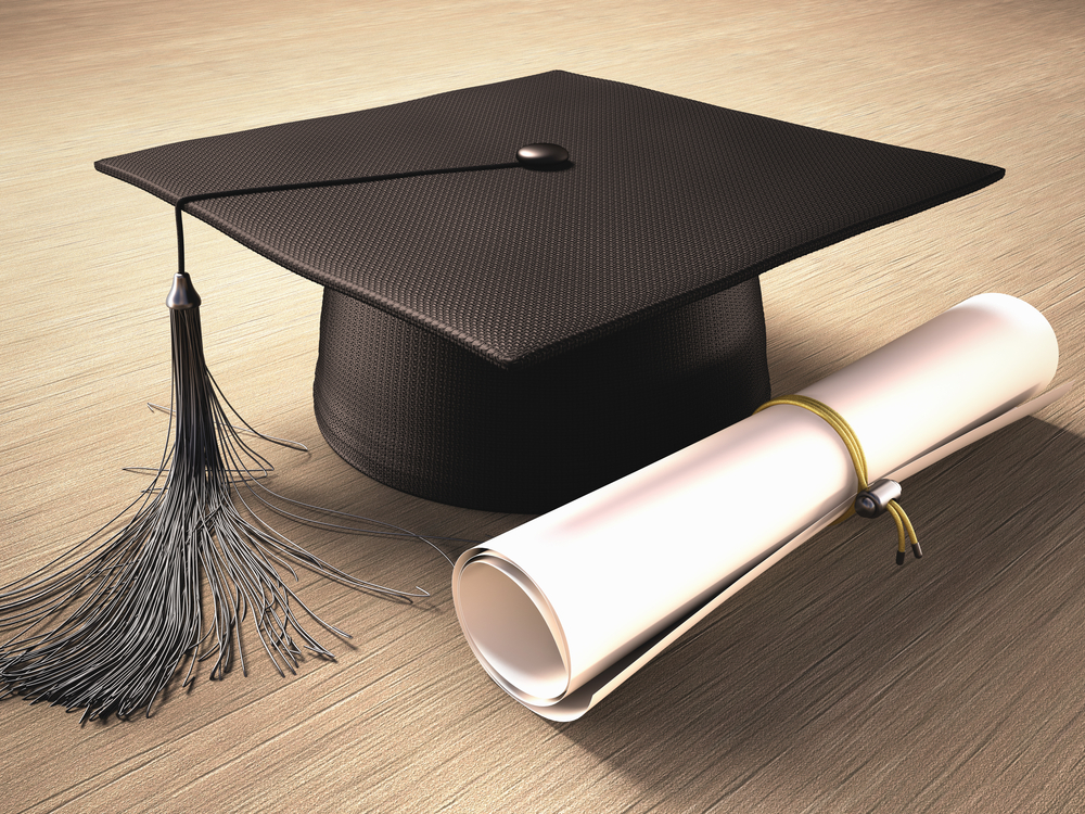 Graduation cap with diploma over the table.